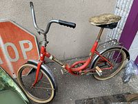 Side view of the red Sabrina bicycle showing frame, handlebar, seat and tires with a STOP sign behind.