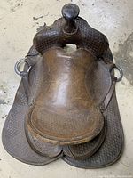 Top-down view of vintage JC Higgins leather horse saddle showing textured embossed pattern and metal rings on sides.
