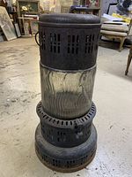 Full view of the vintage heater showing the Pyrex glass midsection and metal top and base perforated for ventilation.