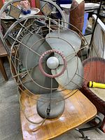 Full view of a vintage Westinghouse electric desk fan showing metal blades, wire protective cage, and base on a wooden table.