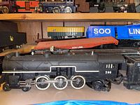 Steam locomotive No. 296 and matching tender in front, SOO Line flat car and blue boxcar behind