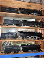 All four locomotives with matching tenders displayed on wooden shelves