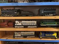 Overall view of eight model train pieces on wooden shelf
