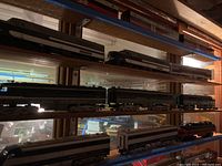 Wooden shelving display of multiple American Flyer diesel locomotives and passenger cars
