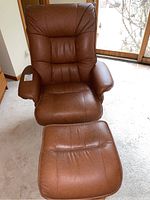 Front view of armchair and ottoman on light carpet beneath window