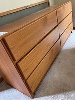 Angled front three-quarter view showing six drawers with integrated handles and wood grain veneer finish.