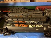 Three black GATX TankTrain tank cars lined up on blue surface