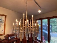 Chandelier hung from electrical track showing full view of metal frame and lucite rods