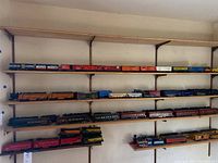 Four-shelf overview showing assorted locomotives, passenger cars, freight boxcars and caboose lined up