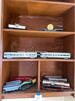 Overall view of three cubby shelves showing a variety of metal and plastic train pieces