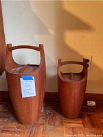Two teak wood ice buckets with lids displayed side by side on parquet floor