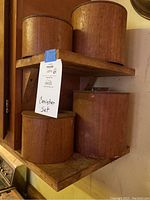 Four wooden canisters on two wooden corner shelves, showing various sizes and wood finish.