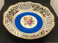 Top angle view of the Schumann Bavaria Dresden Line reticulated porcelain bowl showing colorful floral center with blue band and gold details.