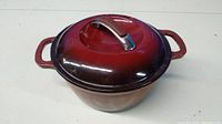Photo of the Dutch oven with the lid on, showing the red to dark gradient enamel and silver handle with KitchenAid branding.