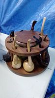 Wooden circular pipe stand with eight wooden pipes slotted around two tiers and a glass jar in the center.