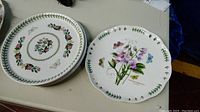 Two plates with floral and butterfly patterns and pierced edges, shown on tabletop surface