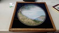 Photo of framed circular landscape print on table.