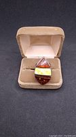 Ring displayed in a beige velvet ring box, showing three triangular amber stones set vertically in sterling silver.