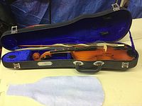 Full view of the child-sized violin inside the open case showing the violin, bow, and blue velvet lined case interior.
