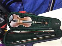 Full view of the child size violin inside its original fitted case, showing the violin body and interior green velvet lining.