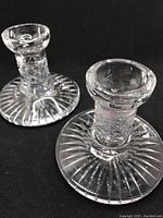 Pair of Waterford crystal candleholders on black background, showing overall design and condition, with one candleholder having a chip at the base