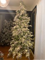 Full view of the 9-foot tall pre-lit artificial Christmas tree with snow-covered branches in a room setting.