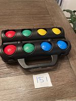 Black molded plastic case holding 8 bocce balls of four colors (red, green, yellow, blue), two of each color.