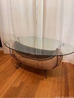 Full view of coffee table showing wooden canoe base, glass top, and metal frame/legs