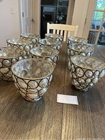 Set of nine distressed mercury glass containers with bubble designs encased in black metal frames all arranged on a wooden table.