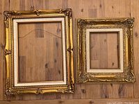 Front view of two gold frames showing ornate decoration and size difference