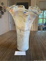 Front view of the hand blown Murano glass vase, showing its fluted, ruffled clear rim with multicolor accents and swirling colored lines throughout the body.
