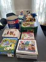 Overview of all toys and games on table including Tinkertoy set, Log Cabin Tree Timbers, plush toys, and board games