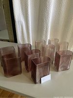 Wide view of all 10 ribbed glass vases displayed on a table, showing overall shape and color.