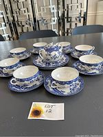 Full set showing six tea cups and saucers, teapot with lid, and three extra plates arranged on a table