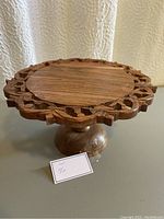 Front view of wooden cake stand showing carved edge and pedestal base