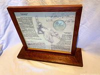 Framed display showing biographical information on Aram Khachaturyan with embedded silver coin and musical notes background.