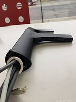 Close-up of matte black Kraus bathroom faucet, showing single lever handle and attached supply lines for counter mounting.