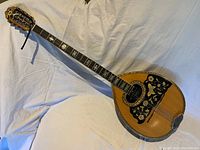 Full view of bouzouki mandolin laid flat on fabric background.