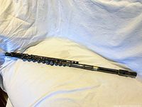 Full length view of the B flute on white fabric showing the instrument in its entirety with keys and headjoint visible.