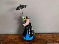 Full view of Mary Poppins figurine standing holding an umbrella and carpet bag.