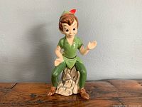 Front view of the Peter Pan ceramic figurine sitting on a tree stump with no visible chips.