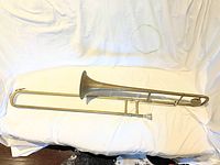 Full-length view of trombone laid flat on white sheet