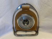 Front view of weather gauge with metal frame and pigskin leather panel showing dial and needle