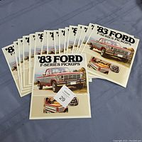 Multiple 1983 Ford F-Series Pickups brochures fanned out on a blue surface, showing front covers with truck images and text.
