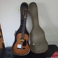 Full view of Anjo acoustic guitar resting in open hard case, showing the guitar body and case interior.