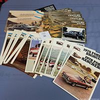 Photo showing an assortment of car dealership brochures from the 1970s and 1980s including Mercury, Pontiac, Buick, and Ford models.