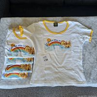 Five white youth large Care Bears T-shirts stacked with yellow collar and sleeve trim.