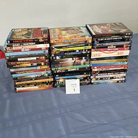 Photo showing three stacks of DVDs with visible titles including action movies, fitness workouts, and classic films.