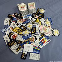 Top-down image showing a large pile of assorted patches spread on a dark fabric background.