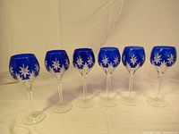 Full view of six cobalt blue crystal wine glasses with floral etched bowls and clear stems/bases.